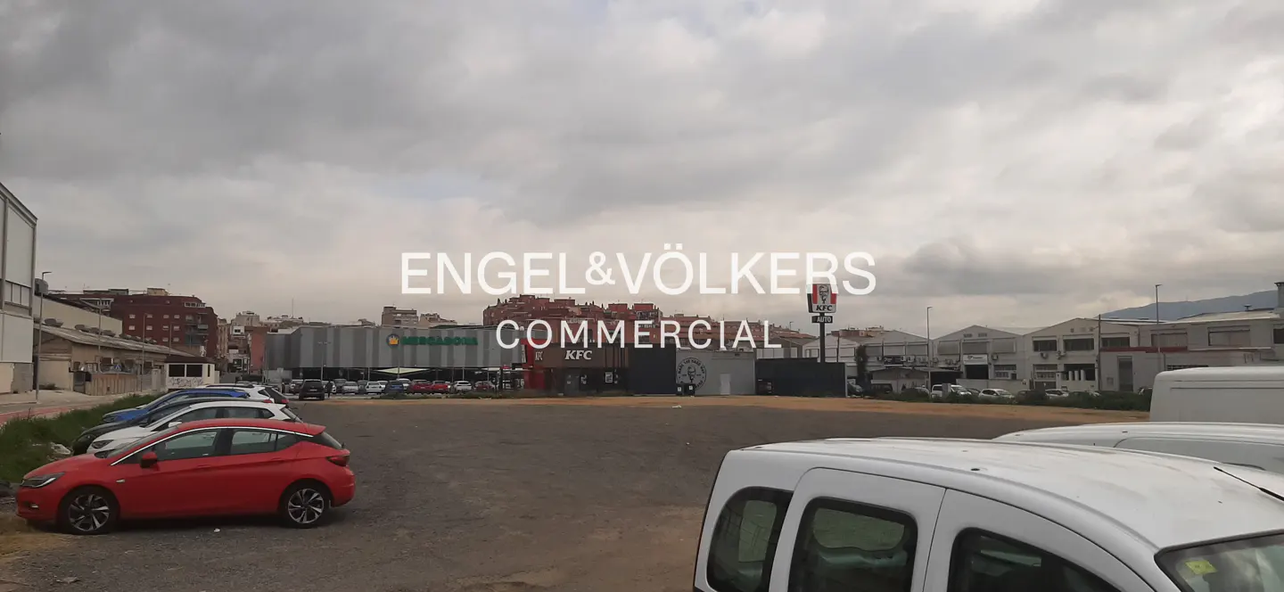 Commercial property with parking lot, Mercadona and KFC in the background, under a cloudy sky. Cars are parked in the foreground.