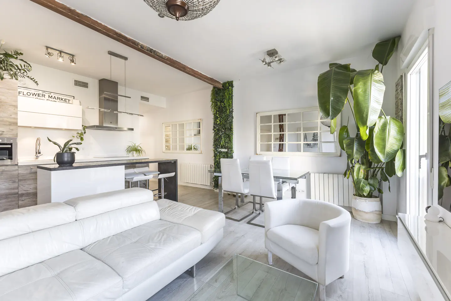 Modern open-plan living room with white leather sofa, dining area, and kitchen featuring a vertical garden wall.