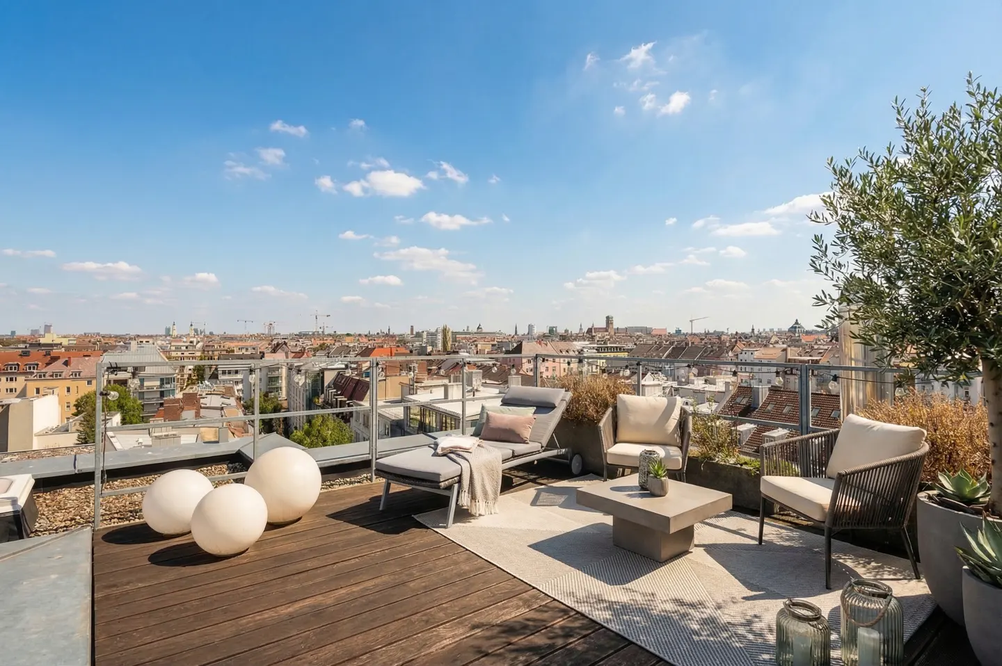 Rooftop patio with lounge chair, two chairs, and a table. City skyline in the background under a blue sky.
