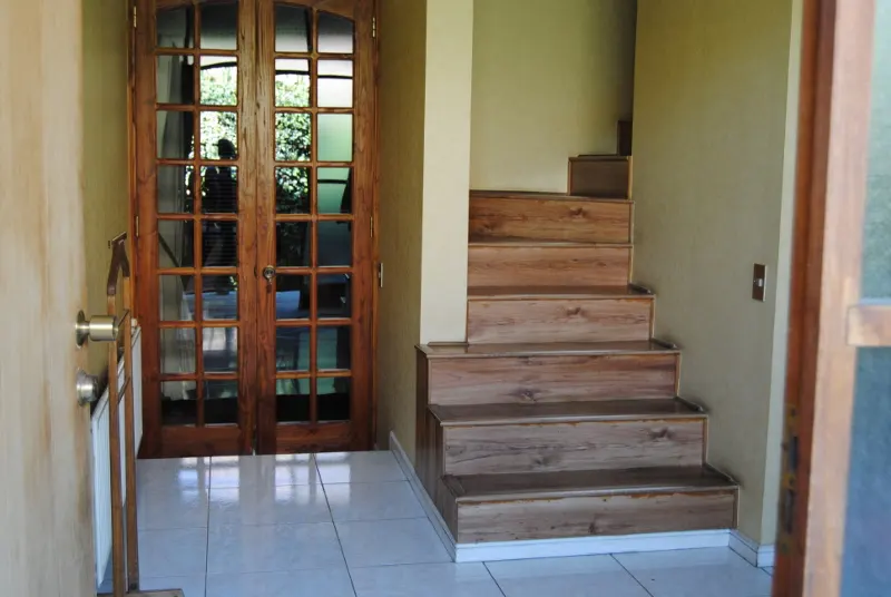 Entryway with wood-framed glass doors, white tile floor, and wood stairs leading up.