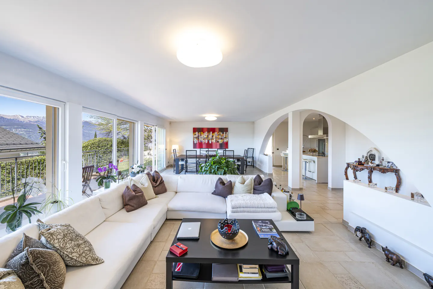 Bright living room with a white sectional sofa, black coffee table, and large windows with mountain views.