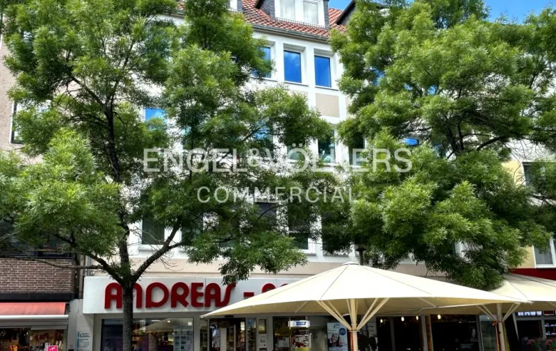 Exterior shot of a commercial building with "ANDREAS" signage, partially obscured by trees and a white umbrella.