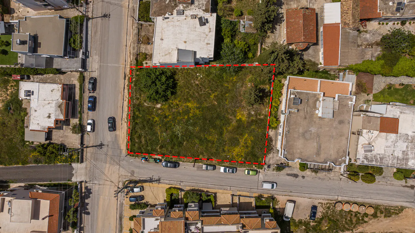 Aerial view of a vacant lot outlined in red, surrounded by streets, parked cars, and buildings.