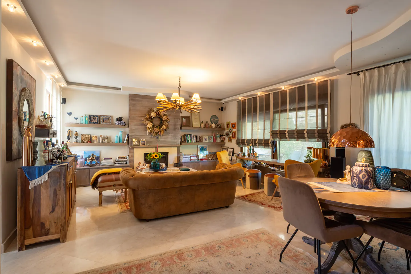 A living room with a brown sofa, a wooden table, and a fireplace with a wreath.