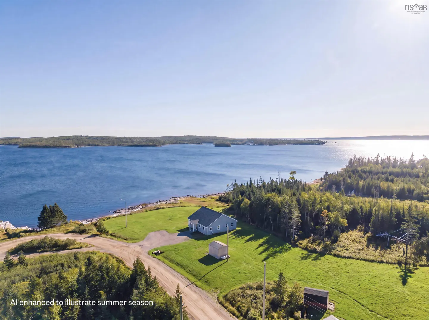 Aerial view of a light blue house with a gray roof, green lawn, and blue ocean in the background.