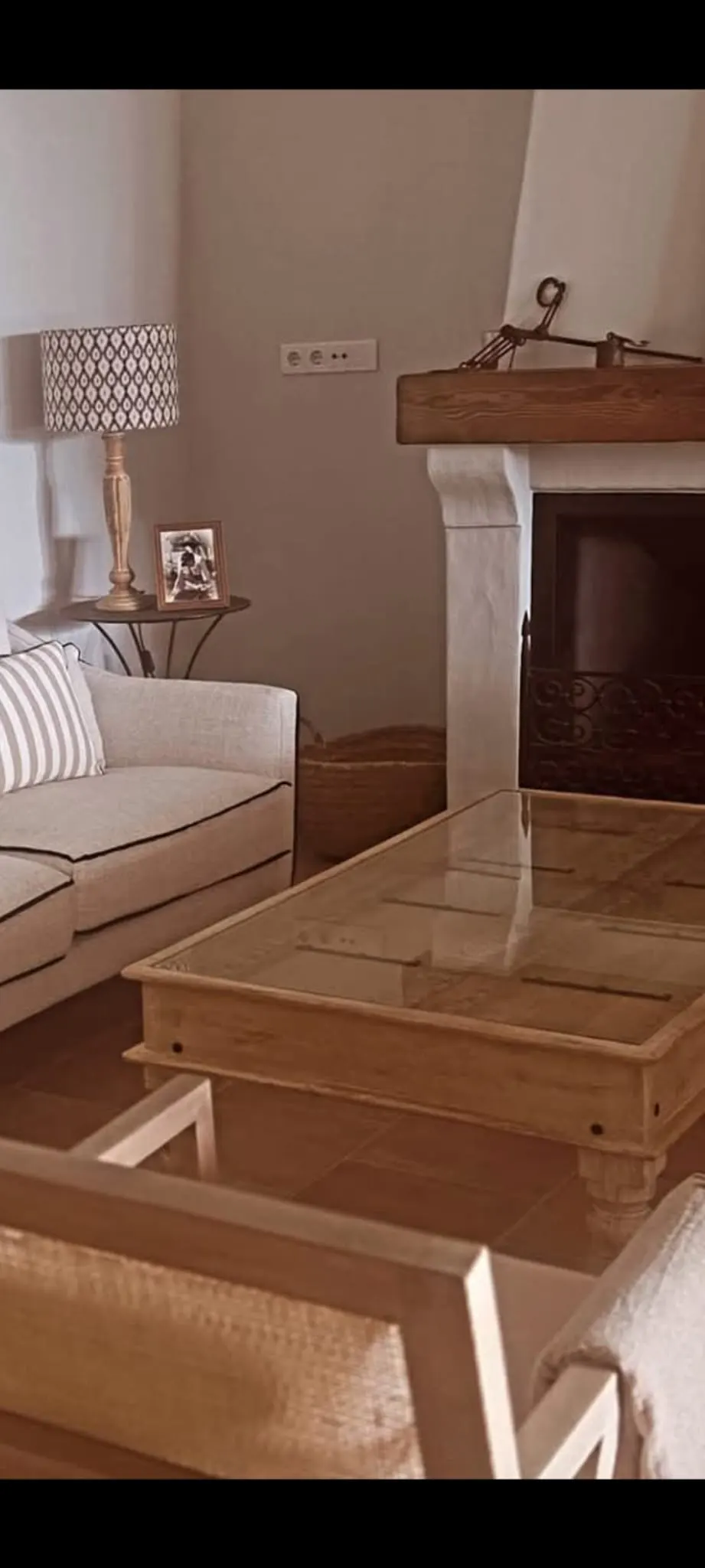 A living room with a beige sofa, a wooden coffee table, and a fireplace with a wooden mantel.