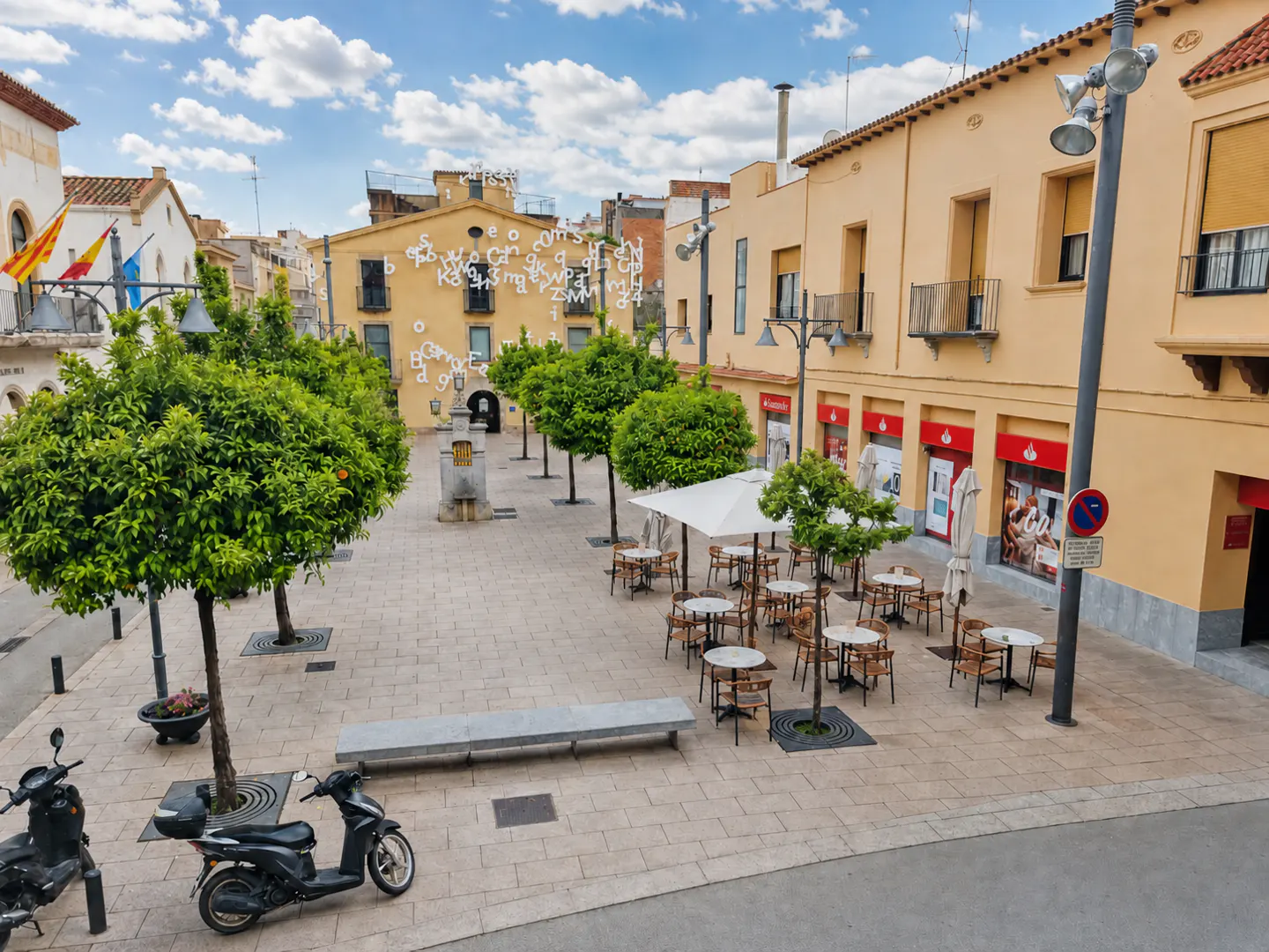 Town square with outdoor cafe, trees, and scooters. Yellow buildings surround the square under a blue sky with clouds.