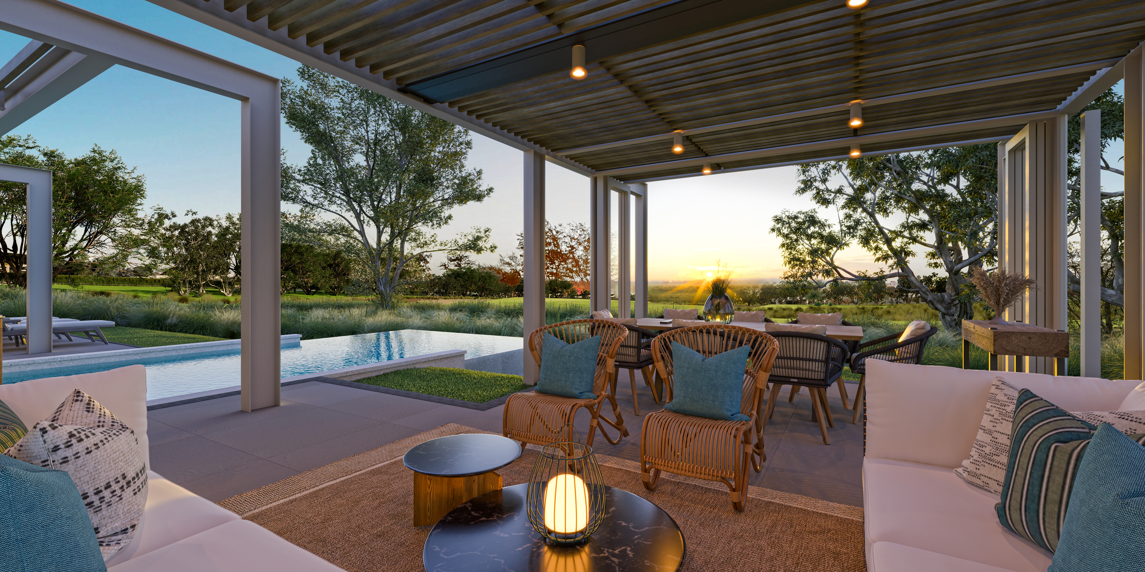 Outdoor patio with white sofas, wicker chairs, and a pool. Sunset in the background.