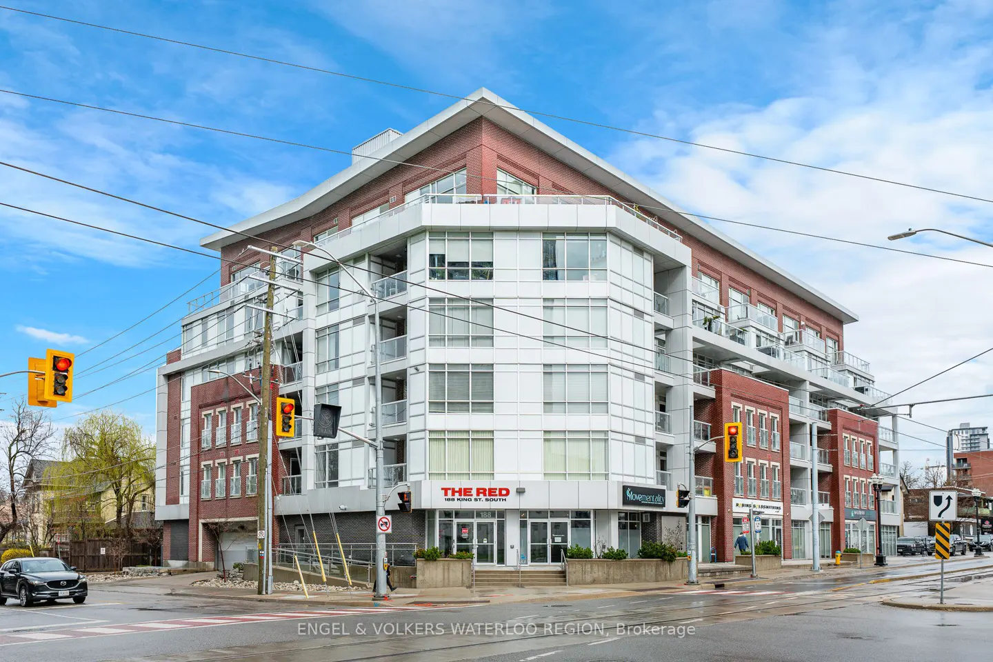 Exterior view of "The Red" building, a multi-story condo with brick and white facade, on a city street with traffic lights.