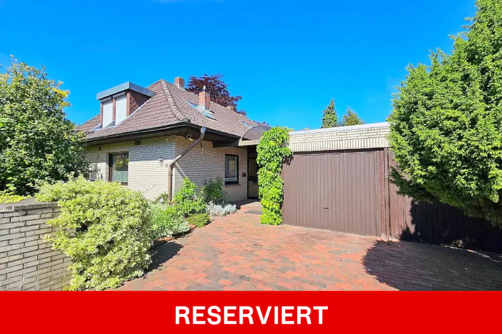 Exterior of a one-story brick house with a brown garage door and a brick driveway on a sunny day.