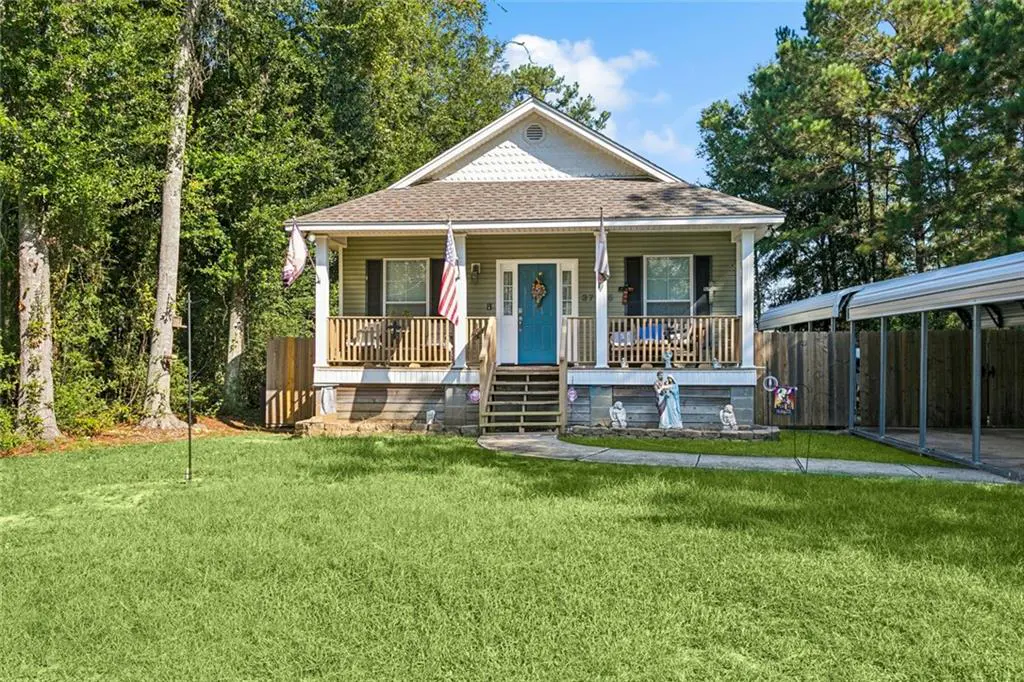 A one-story house with a blue door, a porch, and a green lawn on a sunny day.