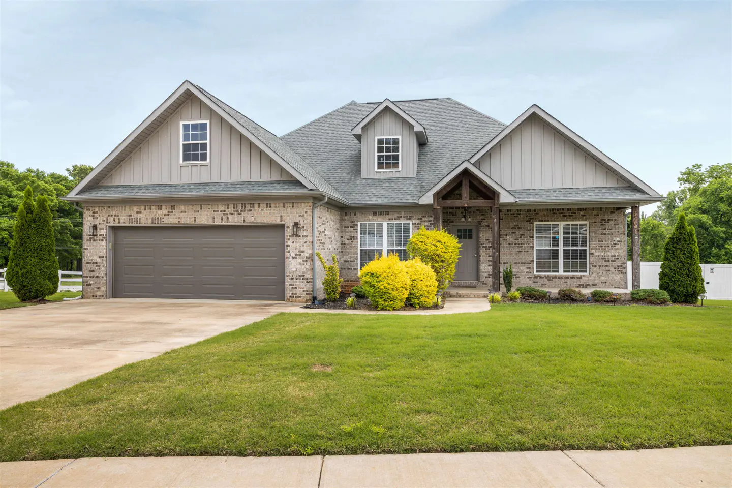 A single-story brick house with a gray roof, a two-car garage, and a green lawn.