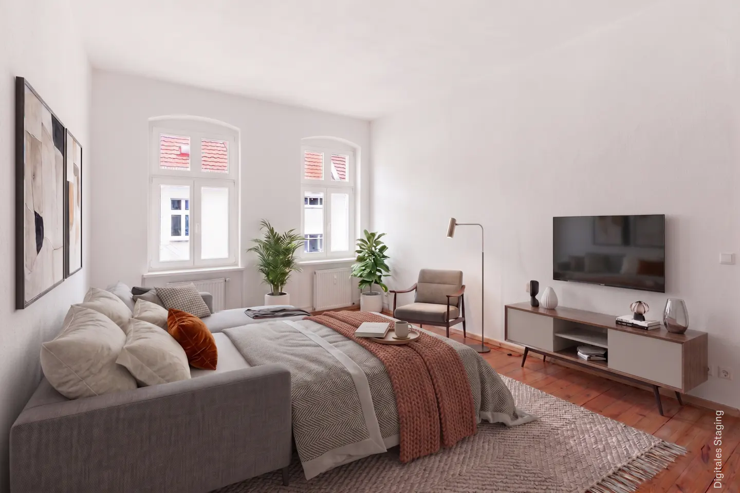 Bright, airy bedroom with a gray sofa bed, TV, console, chair, plants, and two windows. A brown throw blanket is on the bed.