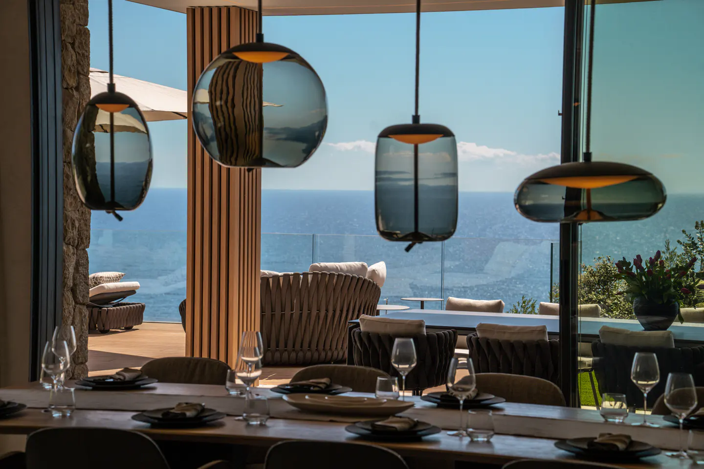 Dining room with a long table set for a meal, pendant lights, and ocean view.