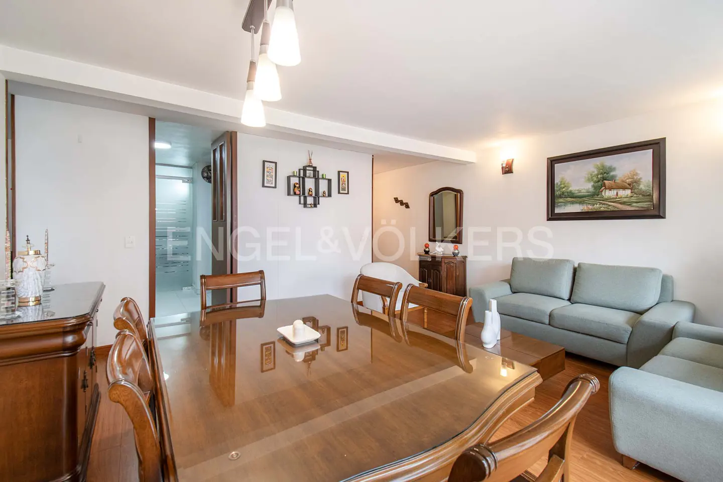 A bright living and dining area with a wood table, chairs, and a light blue sofa.