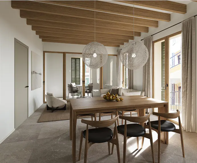 A bright, modern dining room with a wooden table and chairs, two large woven pendant lights, and a view to an outdoor patio.
