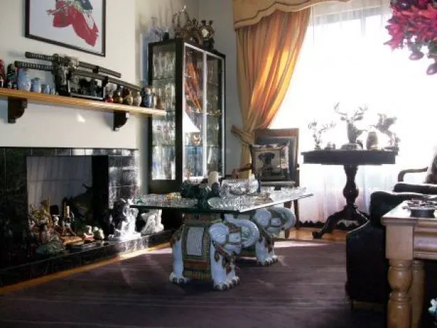 Living room with a glass-topped table supported by elephant statues, a fireplace, and a display cabinet.