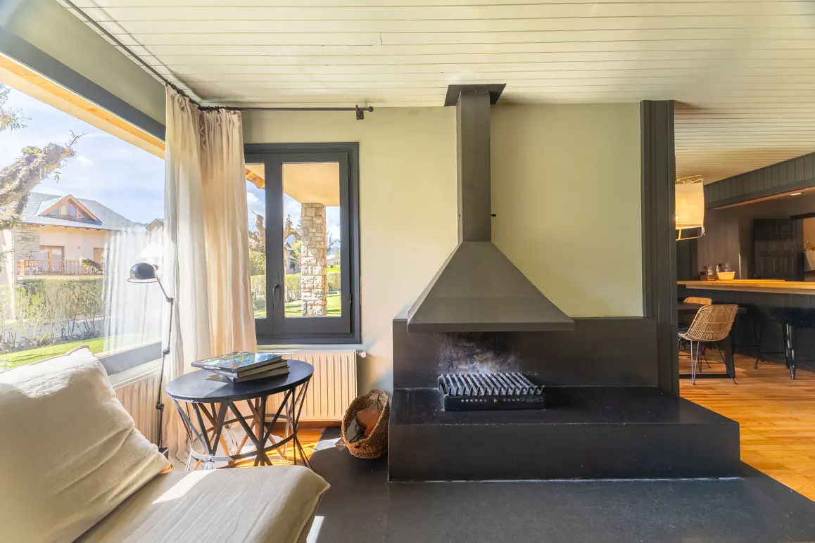Living room with a black fireplace, a chaise lounge, and a view of a house through a large window.