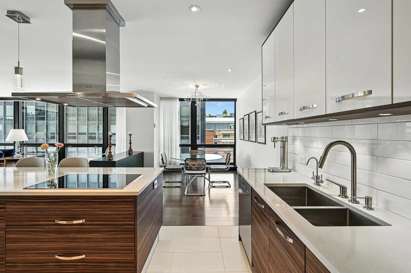 Modern kitchen with white cabinets, wood-grain island, and stainless steel appliances. Dining area visible in the background.
