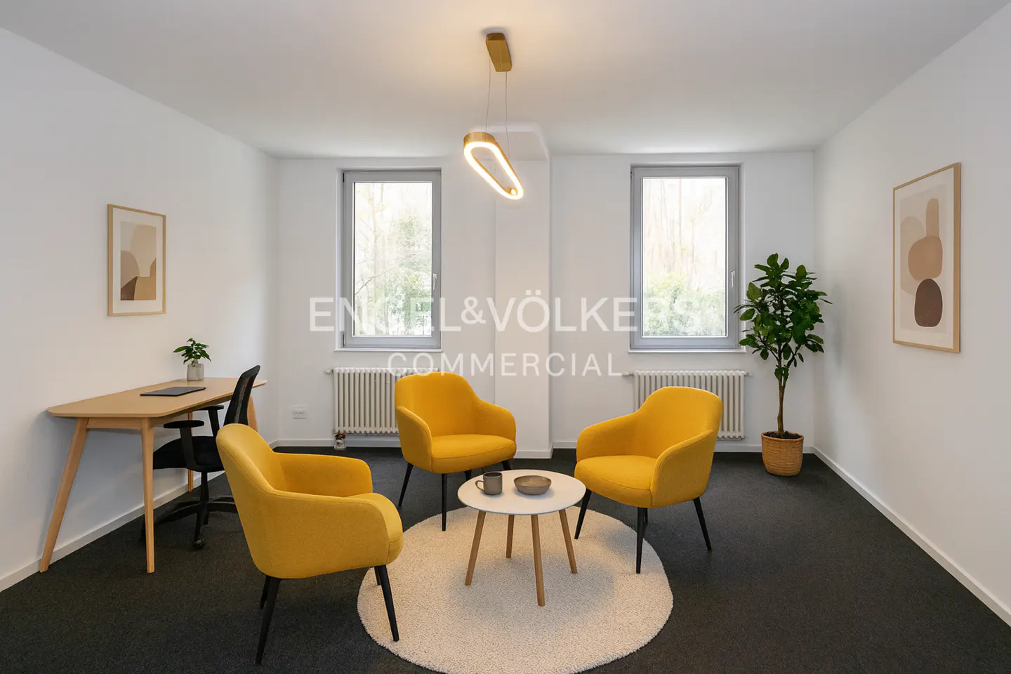 Bright office space with yellow chairs, a white table, and a desk. Modern lighting and artwork add to the clean, professional aesthetic.