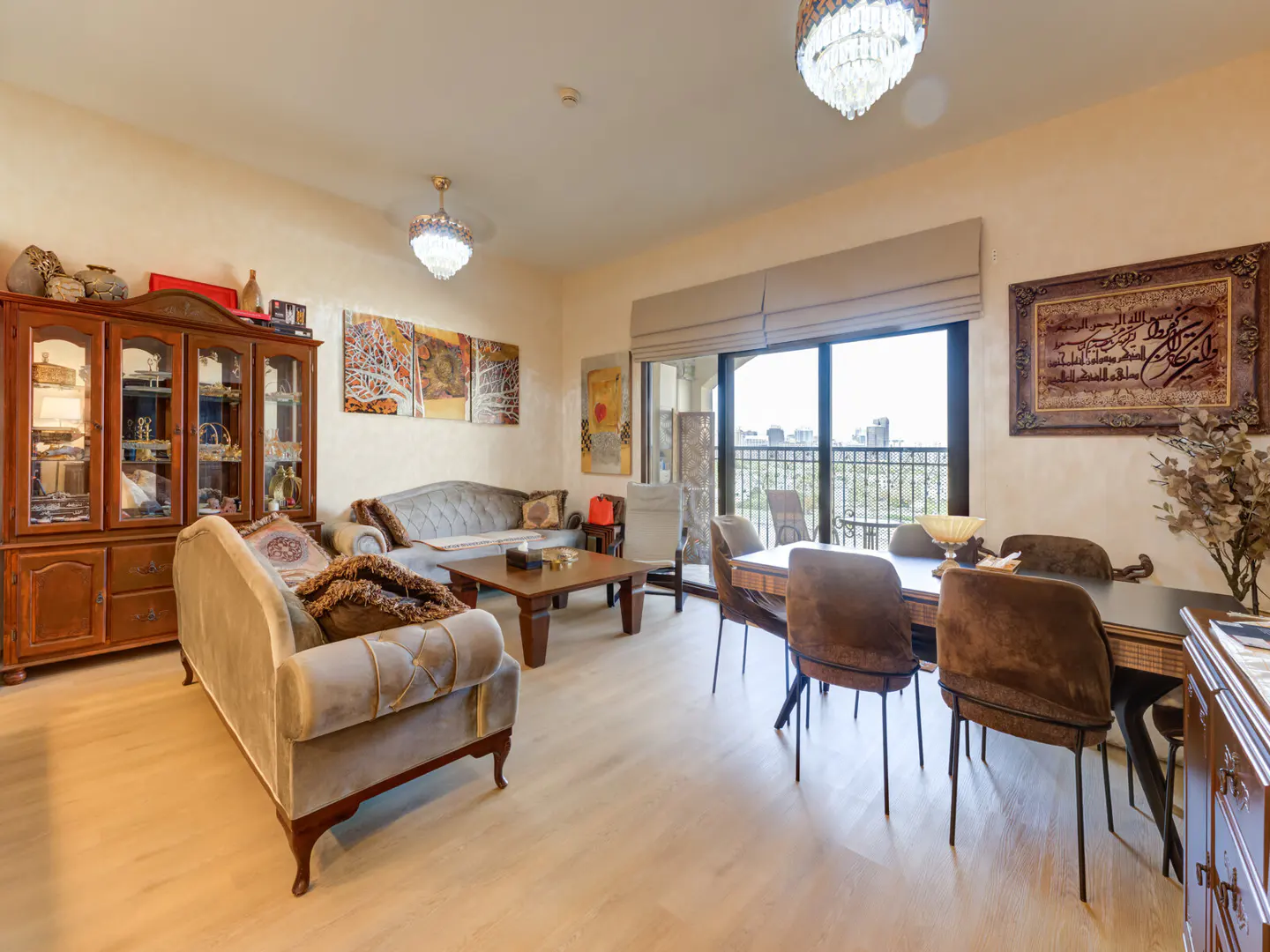 A living and dining area with sofas, a wooden cabinet, a dining table with chairs, and a balcony with a city view.