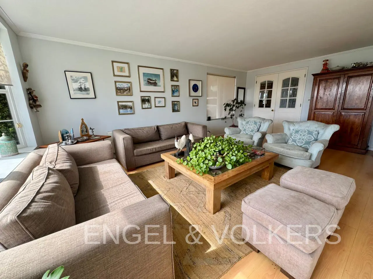 Living room with brown sofas, light blue armchairs, and a wooden coffee table with a plant. Art on the wall.