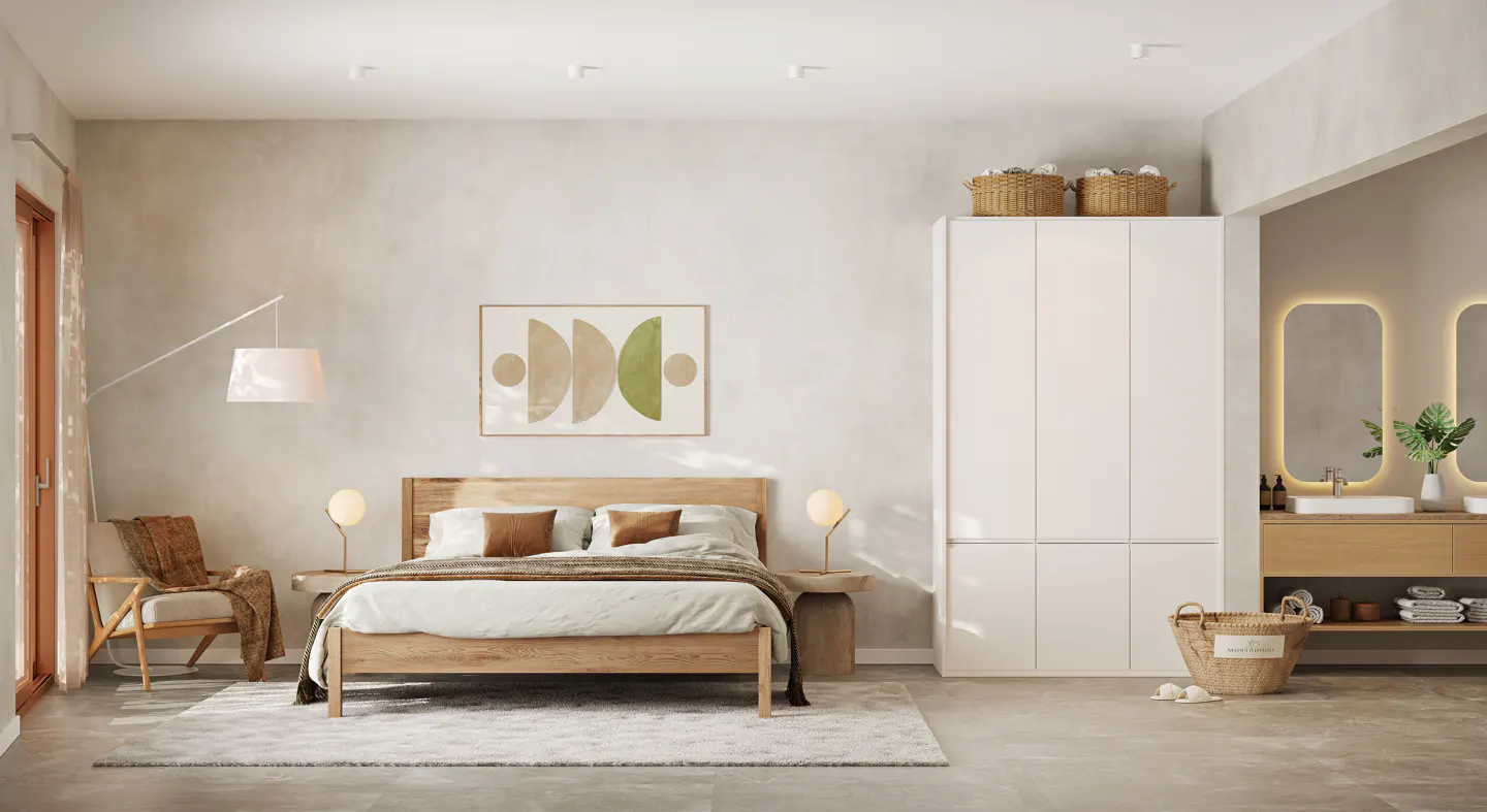 A bright bedroom with a wooden bed, white linens, and a beige throw blanket. A chair with a blanket is on the left, and a white wardrobe is on the right.