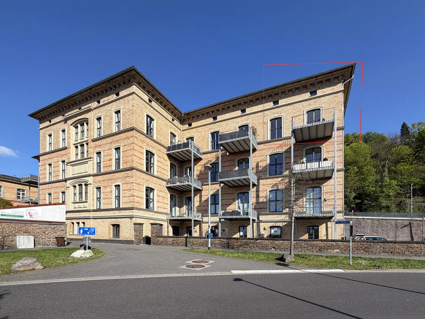 Exterior view of a multi-story brick apartment building with balconies under a clear blue sky.