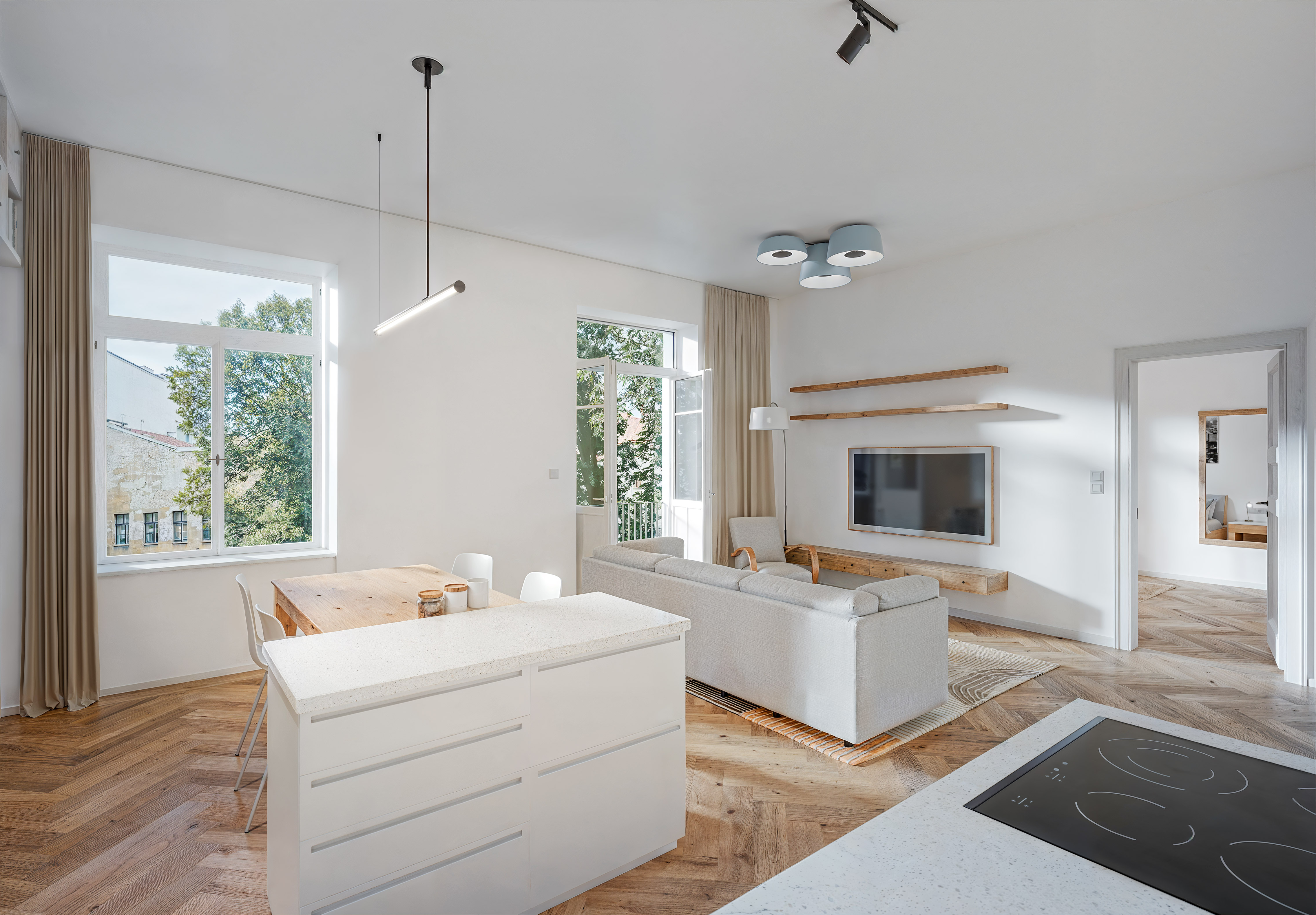 Bright open-plan living area with white kitchen island, wooden dining table, sofa, and herringbone wood floors. [AI-generated text]
