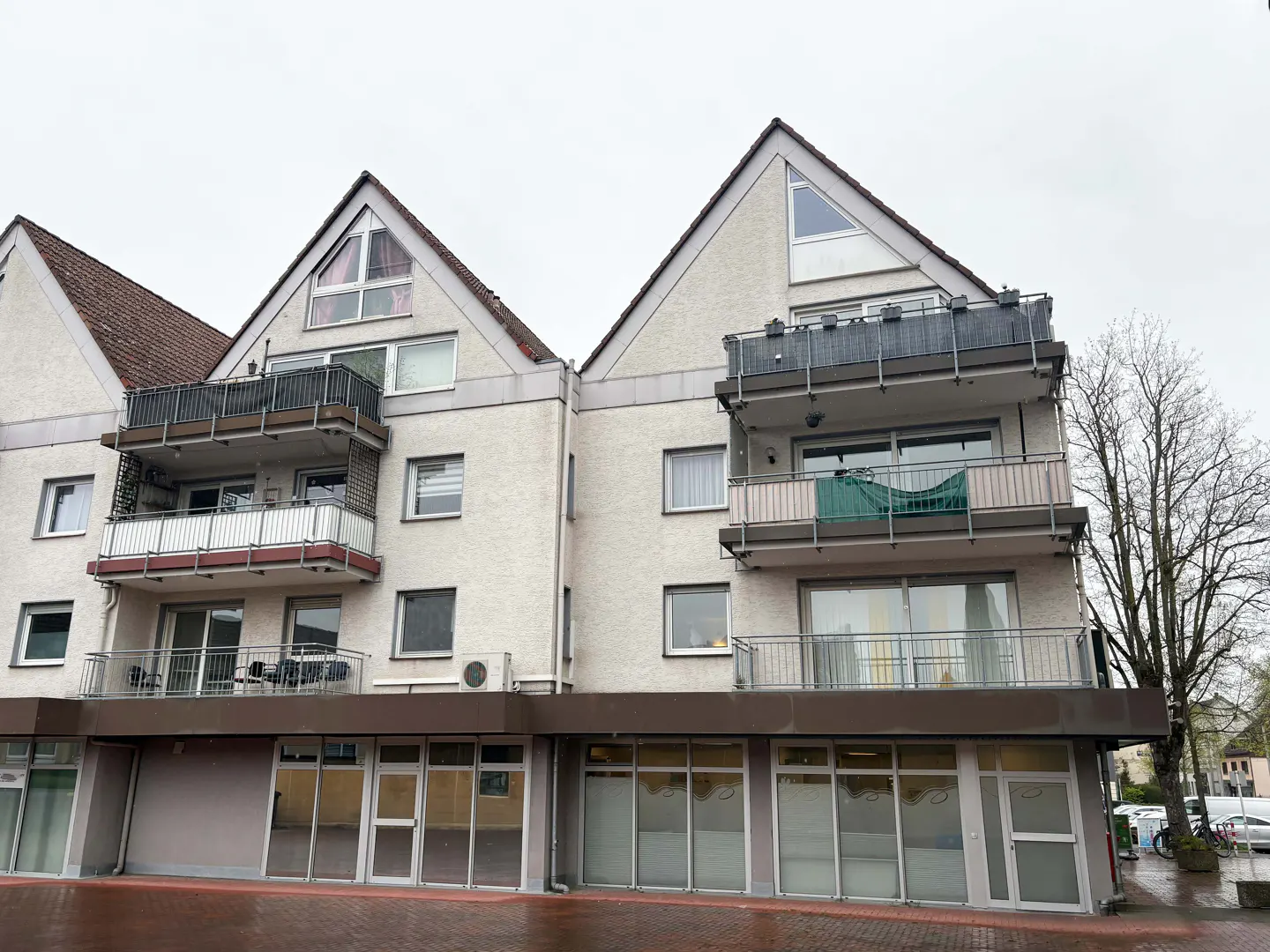 A three-story apartment building with balconies and a commercial space on the ground floor.