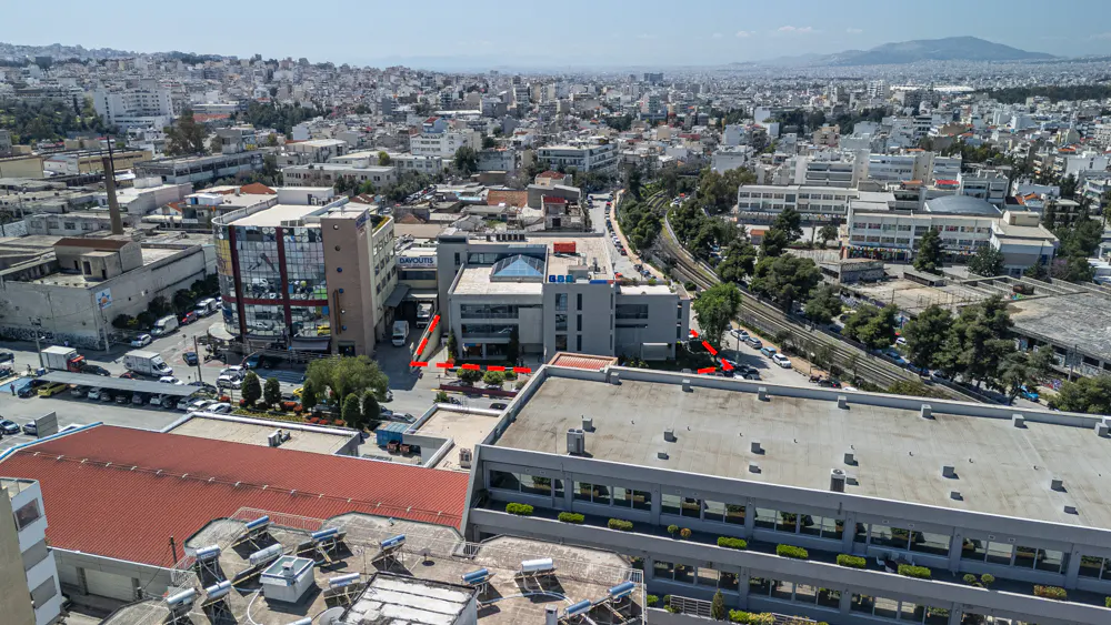 Aerial view of a gray commercial building complex in an urban area with city buildings in the background.