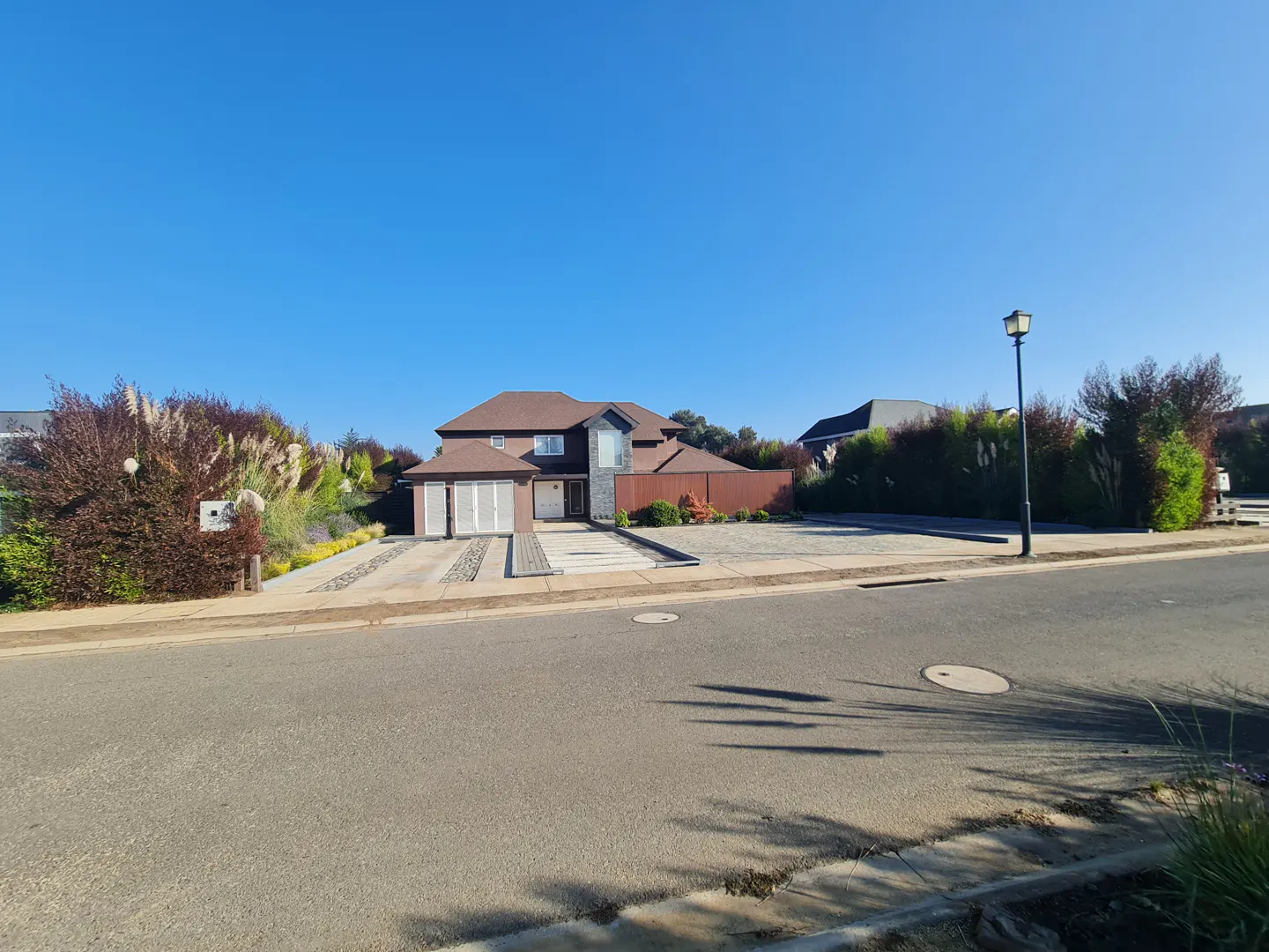 A two-story brown house with a brown roof and a two-car garage on a sunny day.