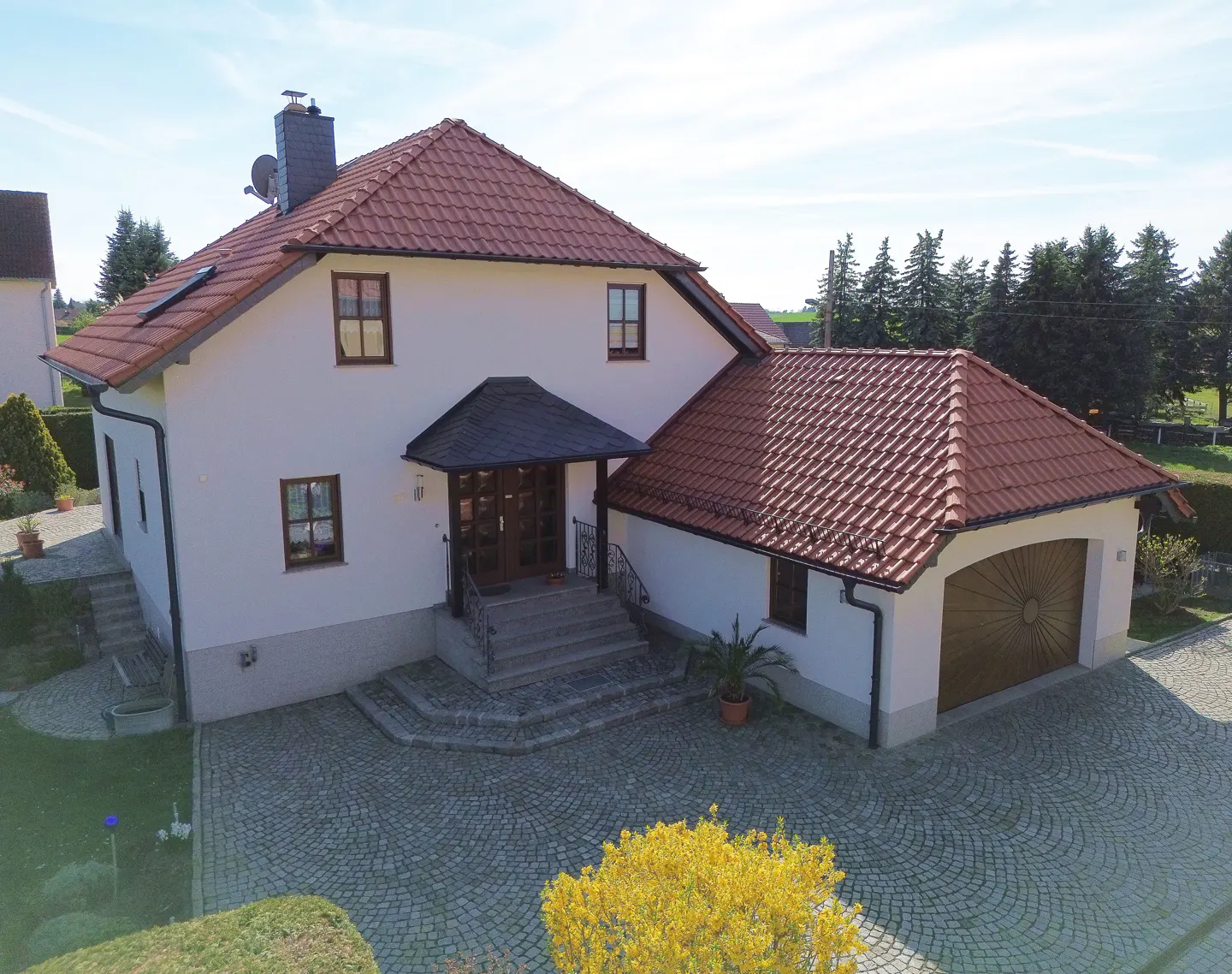 Two-story white house with a red tile roof and a detached garage. A stone walkway leads to the front door.