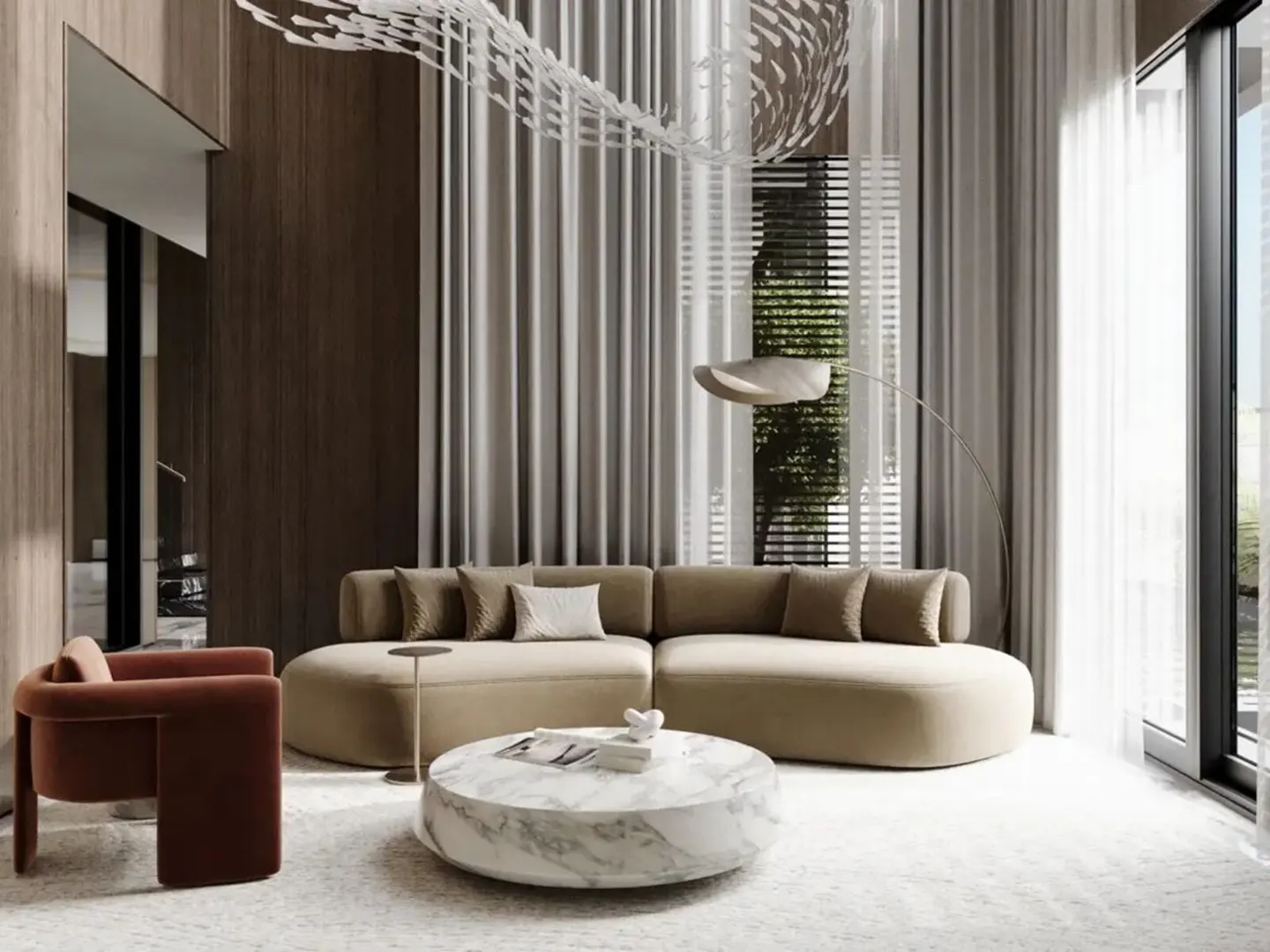 A modern living room with a beige curved sofa, marble coffee table, and rust-colored chair. Sheer curtains and a unique light fixture add elegance.