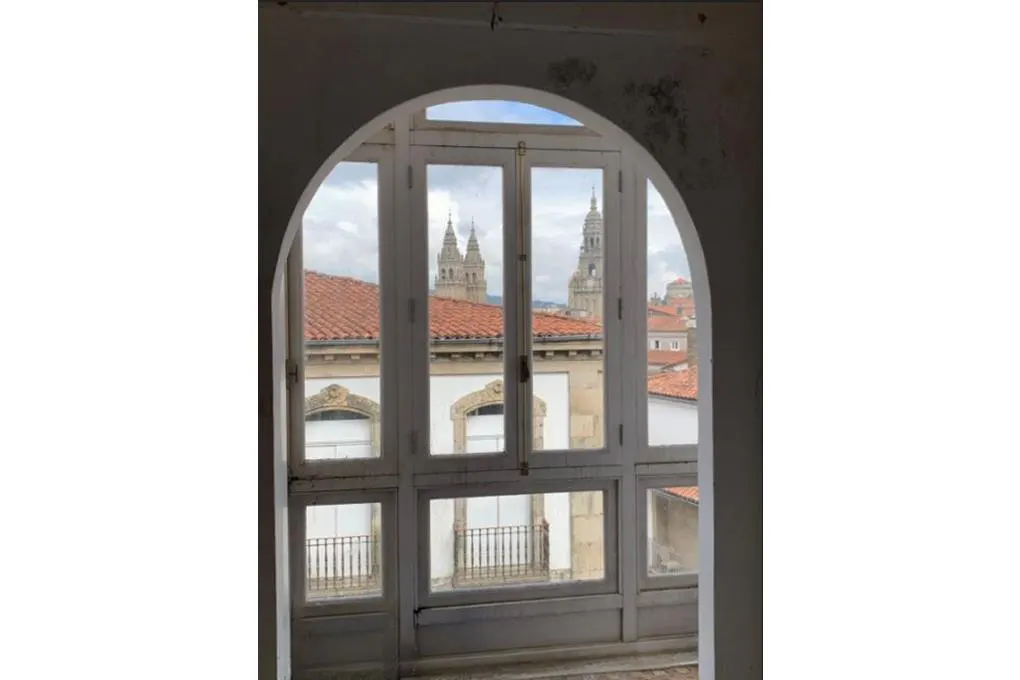 View through arched window of red-tiled roofs and cathedral spires in Santiago de Compostela, Spain.