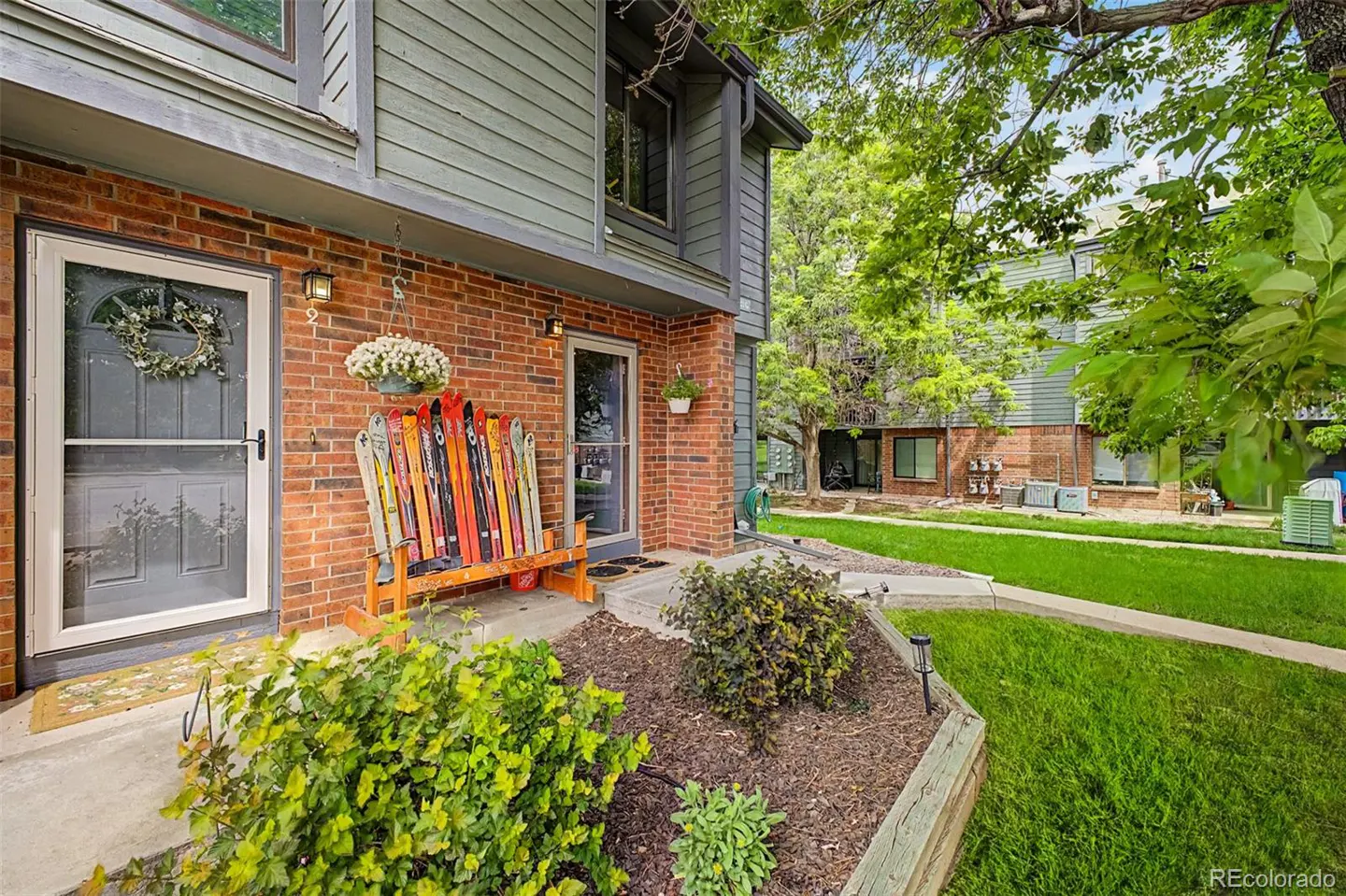 Exterior of a brick townhouse with a bench made of colorful skis on the porch. A wreath hangs on the front door.
