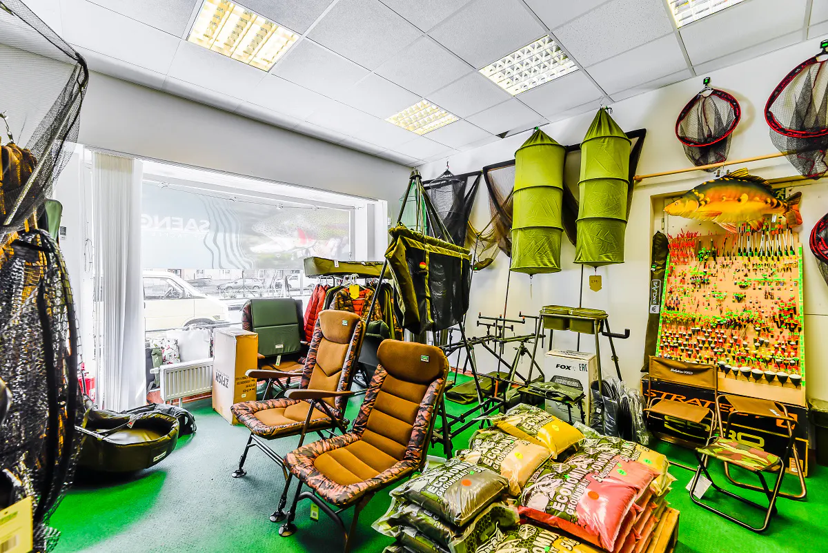 Interior of a fishing store with chairs, nets, fishing rods, and bait on display.