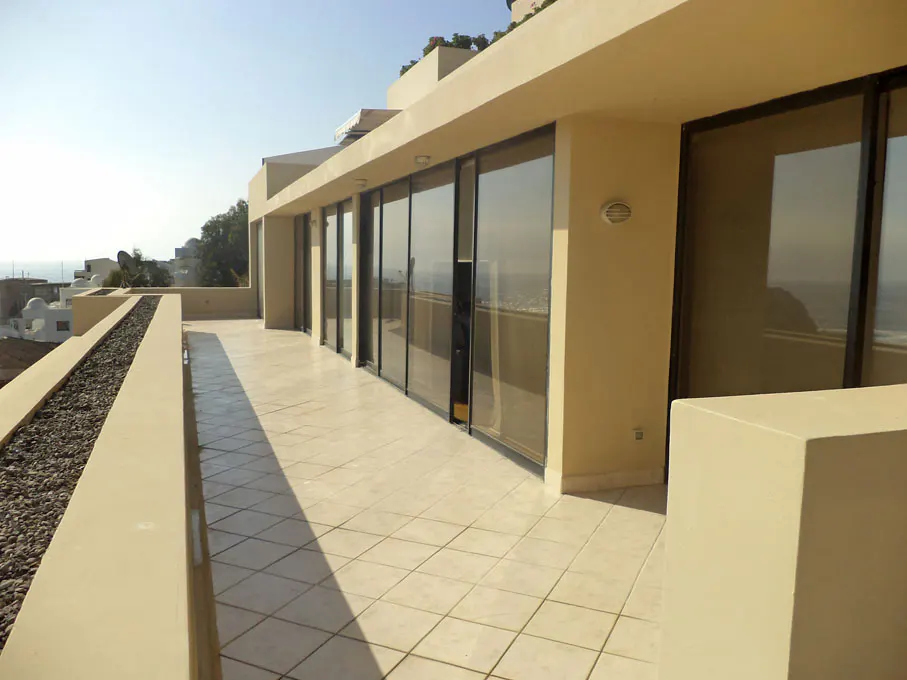 Tan building exterior with a tiled balcony, sliding glass doors, and ocean view.