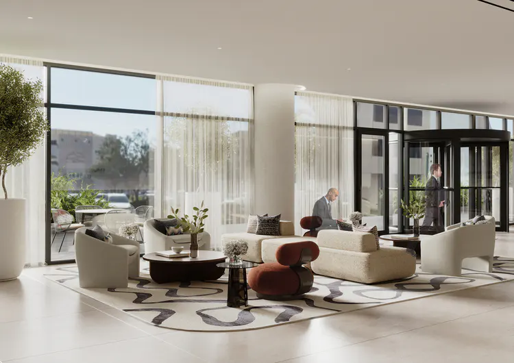 Hotel lobby with beige seating, a patterned rug, and floor-to-ceiling windows. Two men in suits are visible.