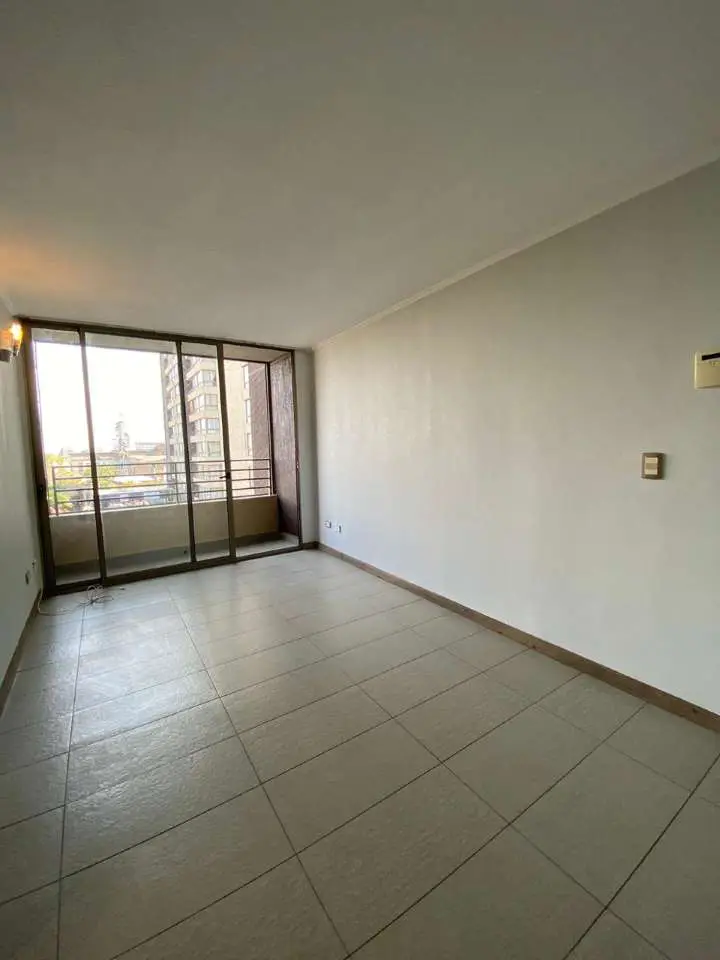 Empty room with white walls and tiled floor. Large sliding glass doors lead to a balcony with city views.