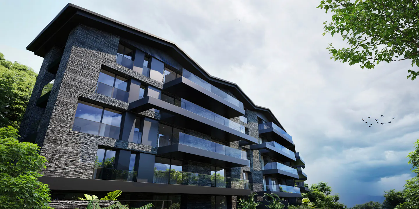 Modern stone apartment building with glass balconies, surrounded by green trees and a cloudy sky.