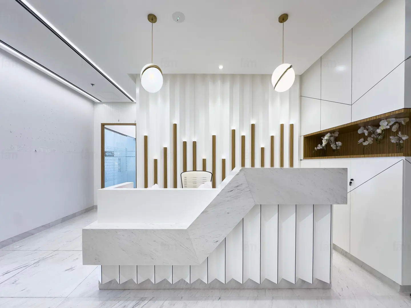 Modern office reception area with a white marble desk, wood accents, and globe pendant lights.