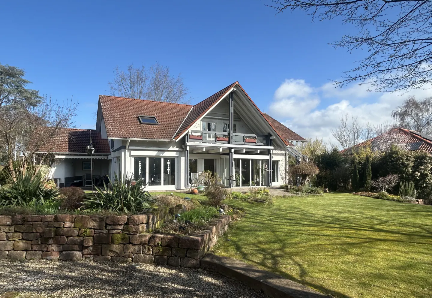 A white house with a red tile roof and a green lawn under a blue sky.
