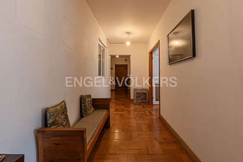 Hallway with parquet floor, white walls, wooden bench with pillows, window, and a framed picture on the wall.