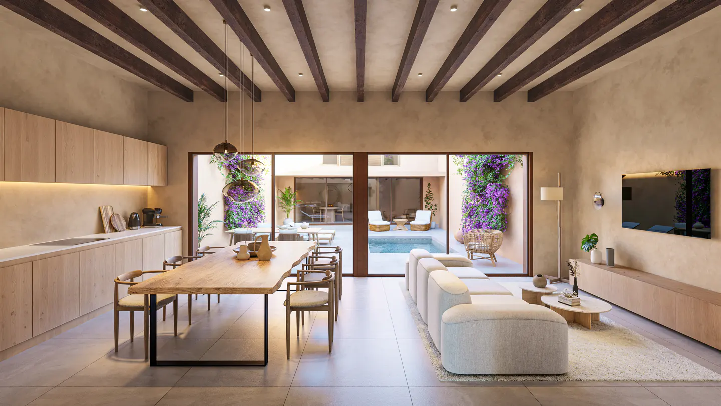 Open-concept living space with a long wood table, light sofa, and pool view. Exposed beams on the ceiling. Neutral color palette.