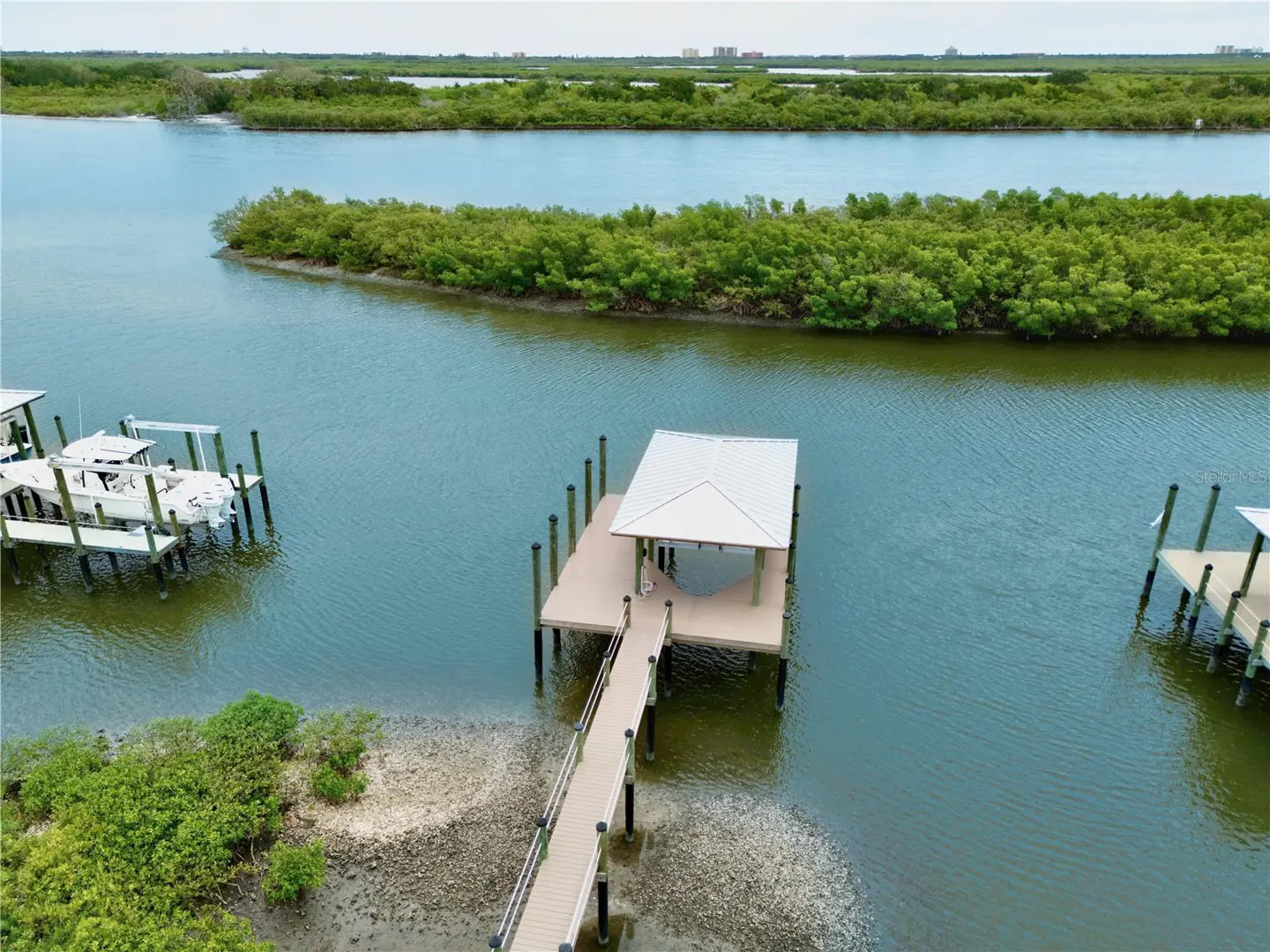 Aerial view of a dock with a boat lift on a waterway with green vegetation in the background.
