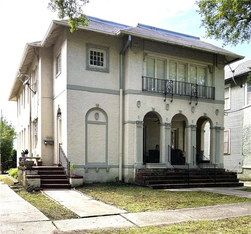 Exterior view of a two-story stucco apartment building with arched entryways and a black iron balcony.