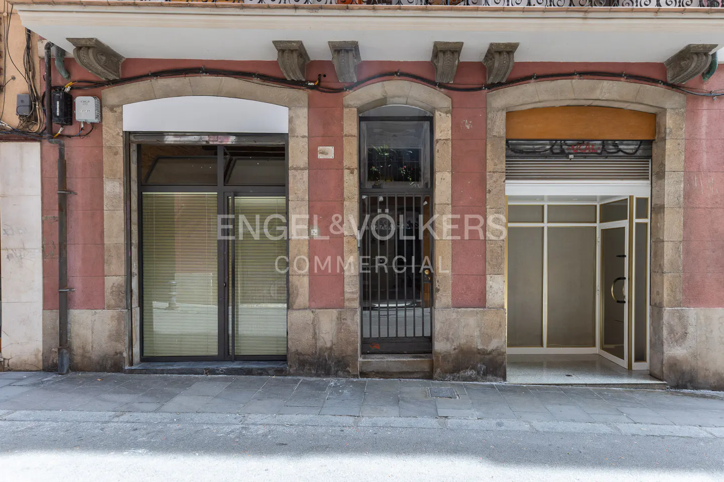 Storefront with three entrances, each framed in stone, with Engel & Volkers Commercial logo on the center door.