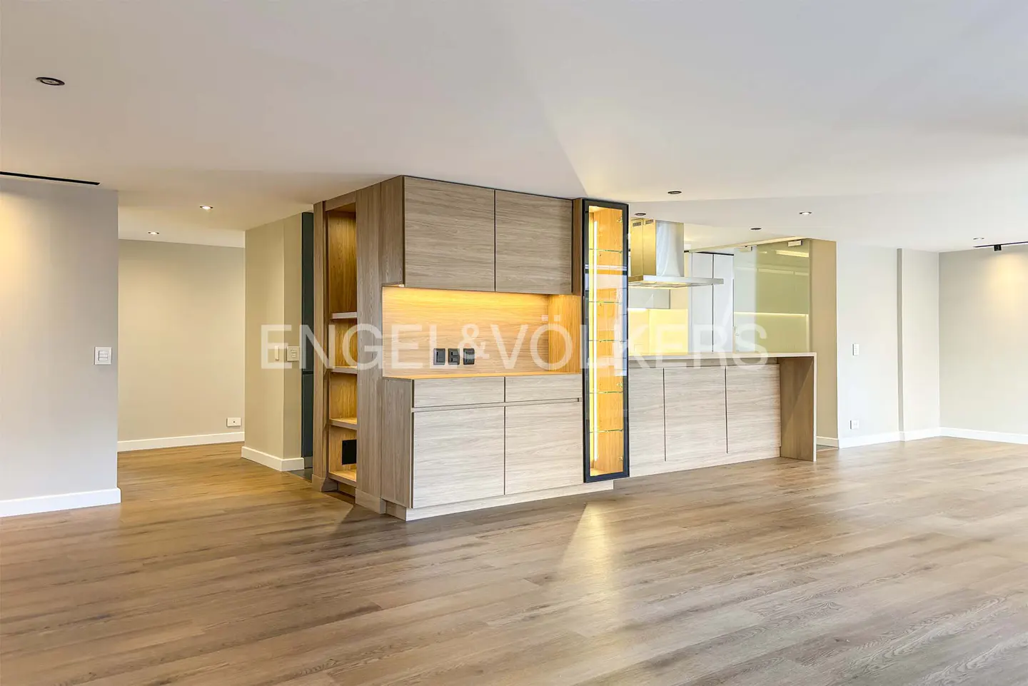 Open-concept kitchen with light wood cabinets, hardwood floors, and recessed lighting.