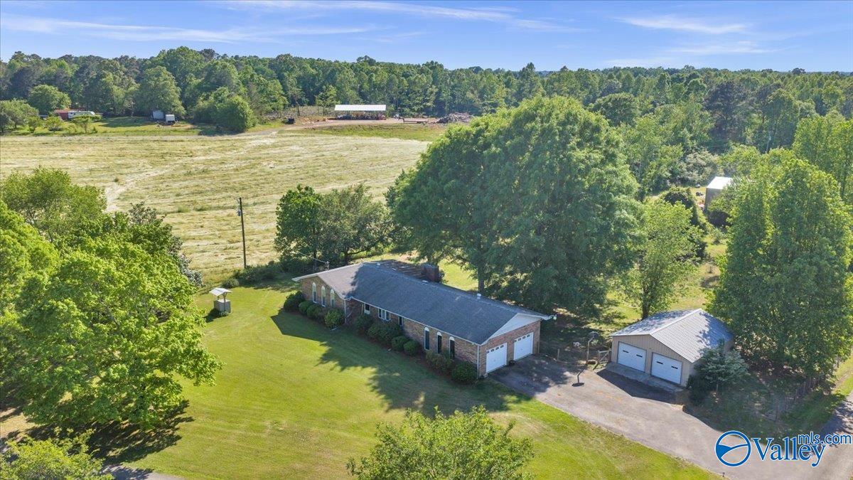 Aerial view of a brick ranch house with a two-car garage and a detached garage on a green lawn with trees.